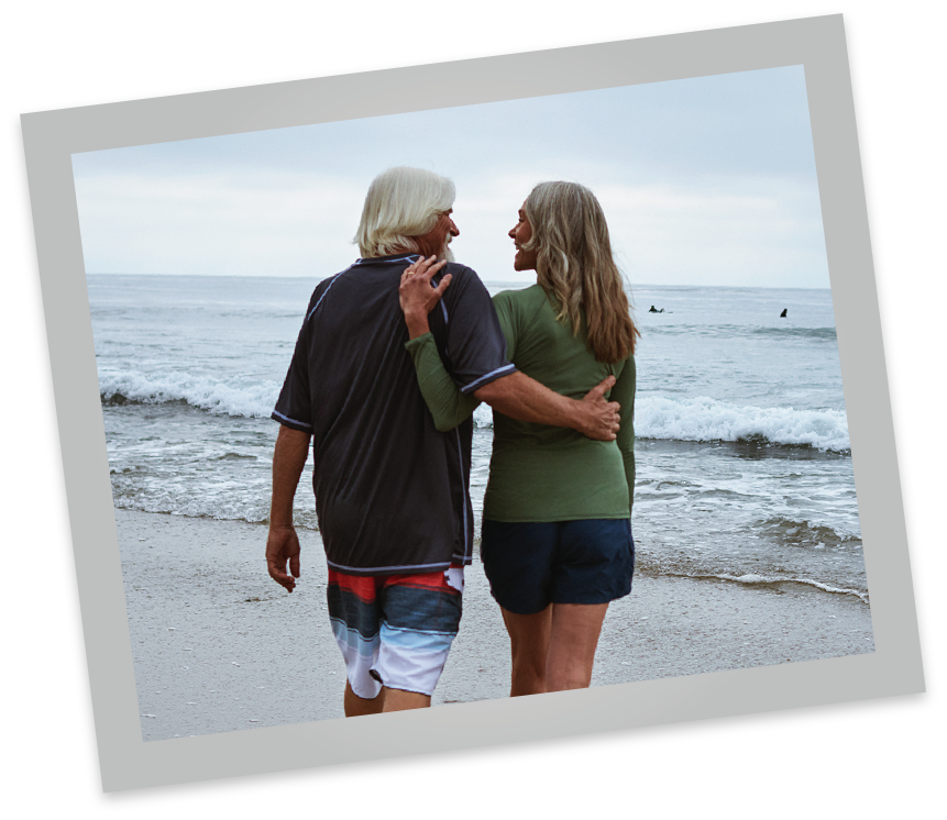 Couple holding each other at beach The backside of a couple with arms around each other at the beach